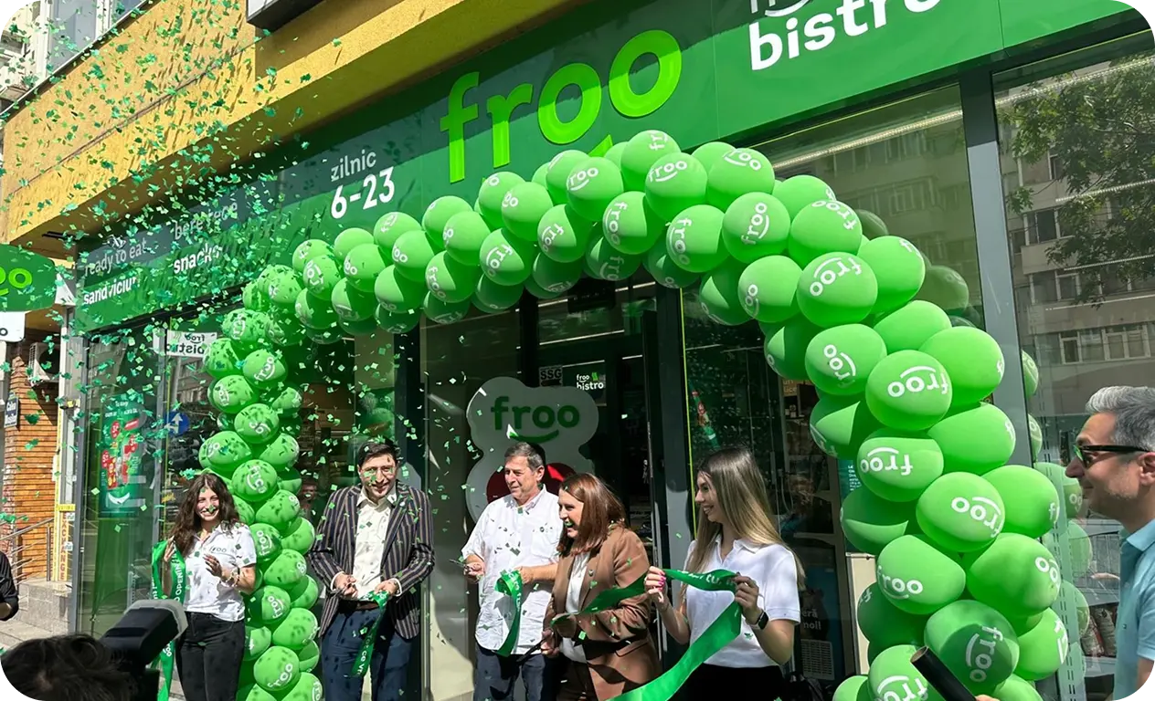 Uroczyste otwarcie sklepu Froo w Rumunii: przecięcie zielonej wstęgi otoczonej bramą z zielonych balonów przed wejściem.